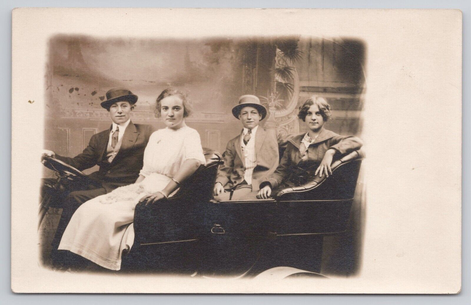 Family of 4 Sitting in a Prop Antique Car Formal Attire c1904-1918 RPPC Postcard