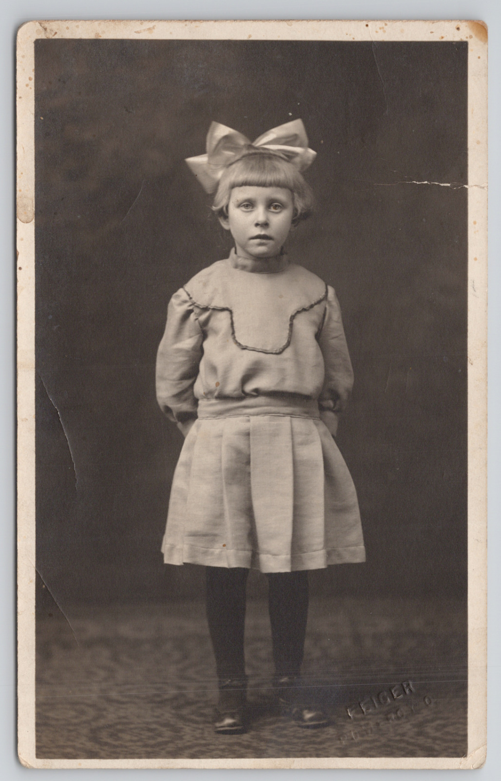RPPC Little Girl With Big Hair Bow Standing In Studio c1910  Real Photo Postcard